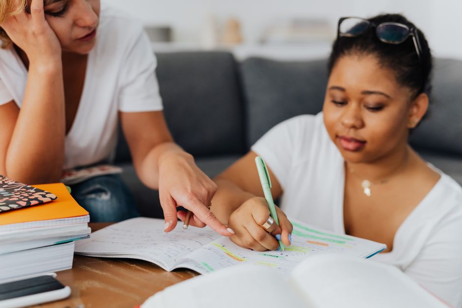 A tutor pointing out a correction in a student's notebook during a coaching session